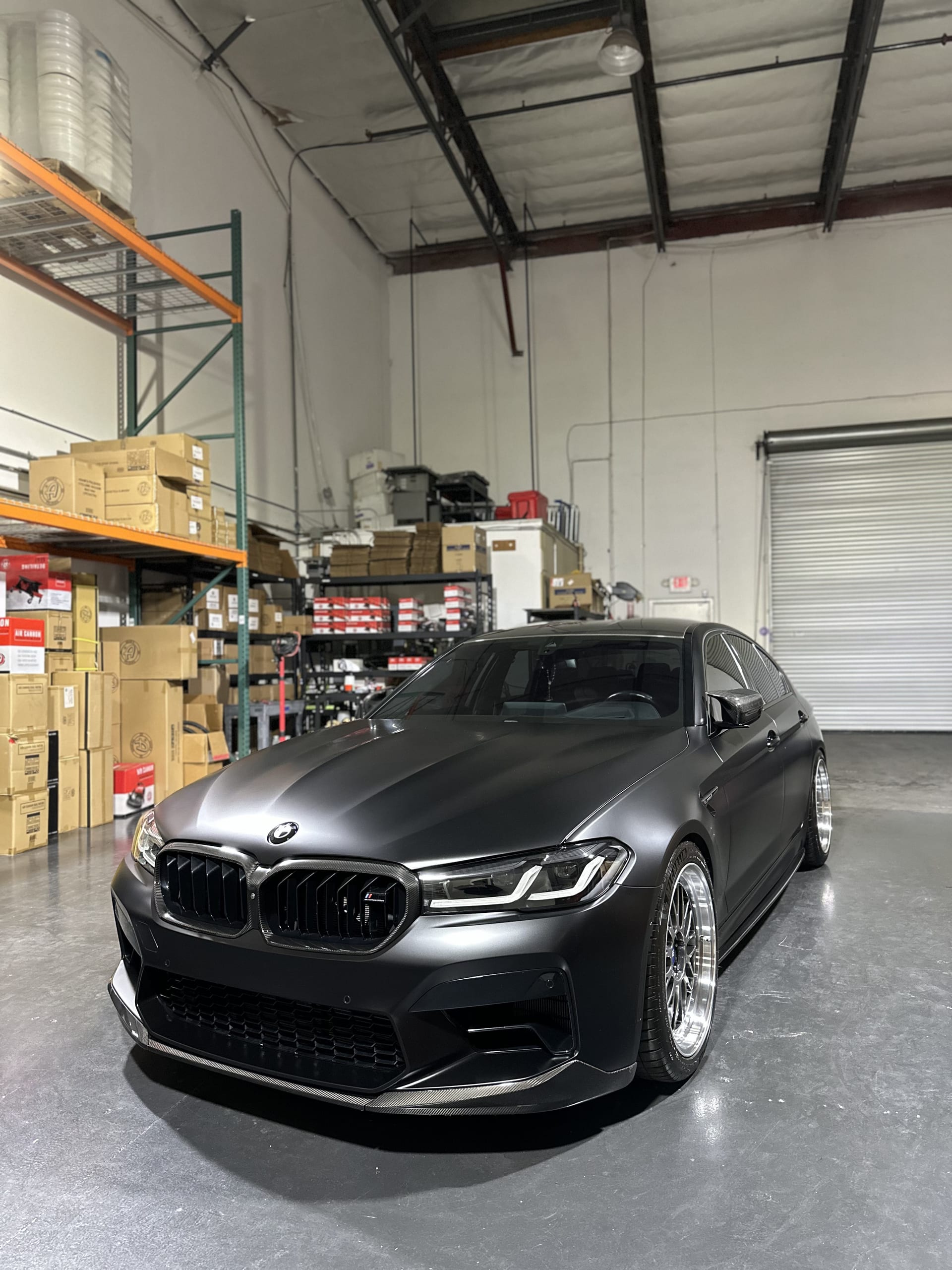 Matte black BMW M5 with carbon fiber lip and custom wheels after full detail