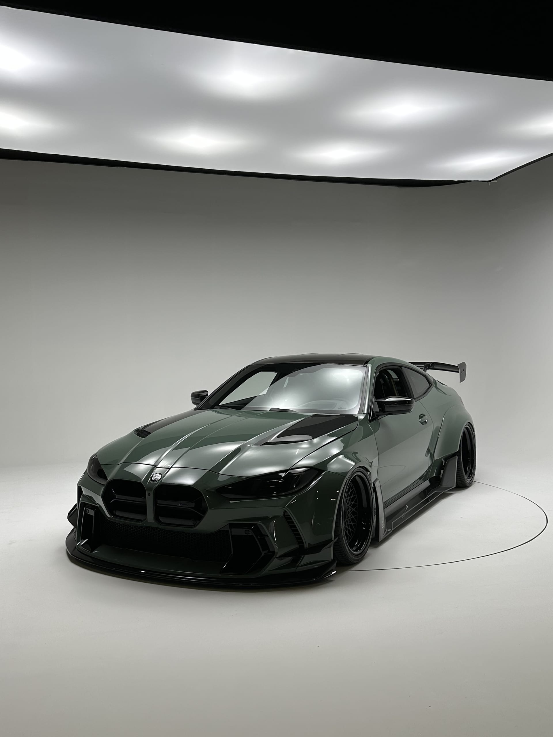 Dark green widebody BMW M4 with paint correction under studio lighting